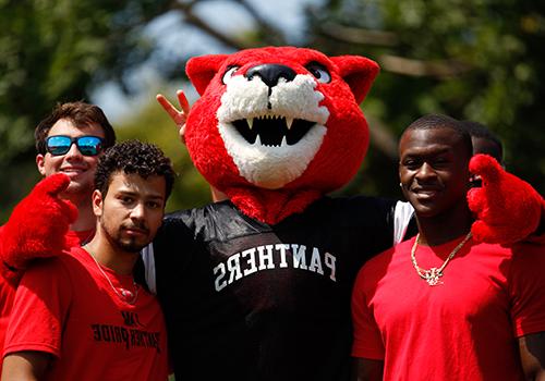 Three students pose with the college mascot, Pouncer